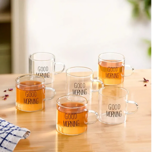 Clear glass mugs with 'Good Morning' text filled with a warm beverage on a wooden surface.