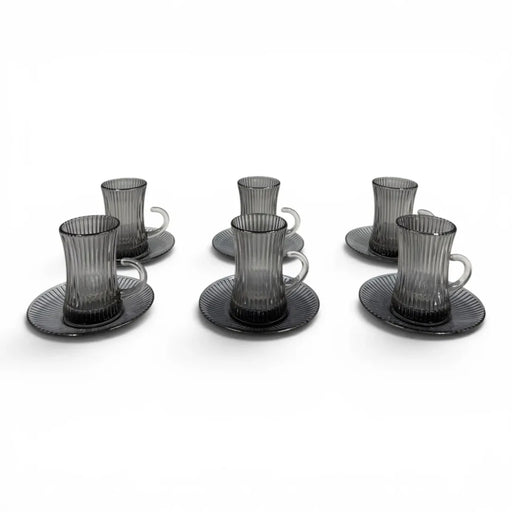 A complete 12-piece smoky grey glass tea service set showing six vertical ribbed glasses with handles sitting on their matching fluted saucers on Spotngrab Lebanon.