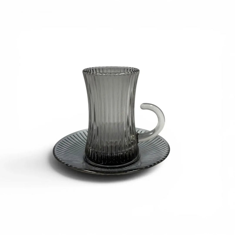 A complete 1-piece smoky grey glass tea service set showing  vertical ribbed glasses with handles sitting on their matching fluted saucers on Spotngrab Lebanon.