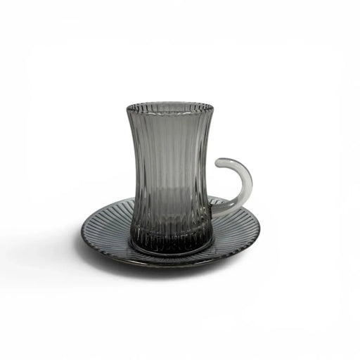 A complete 1-piece smoky grey glass tea service set showing  vertical ribbed glasses with handles sitting on their matching fluted saucers on Spotngrab Lebanon.