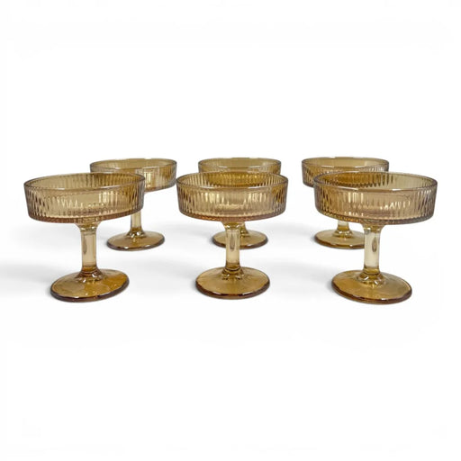 A set of six short-stemmed amber glass champagne coupes displaying a distinct vertical ribbed ripple pattern across their wide shallow bowls on Spotngrab Lebanon.