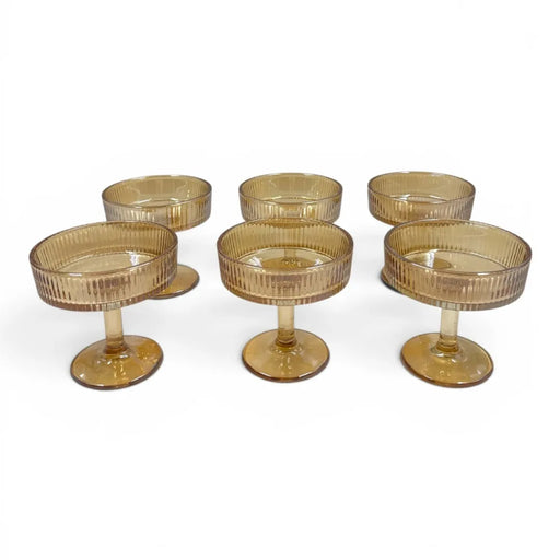 A set of six short-stemmed amber glass champagne coupes displaying a distinct vertical ribbed ripple pattern across their wide shallow bowls on Spotngrab Lebanon.